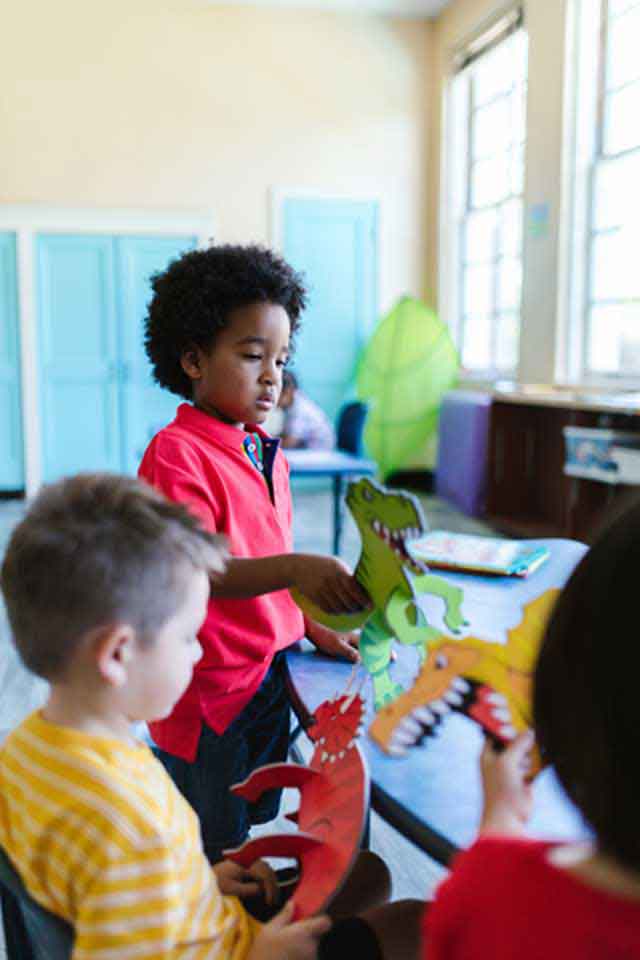 Small kids playing with dinosaur toys inside the classroom